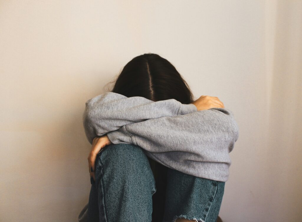 woman sitting with her arms covering her face