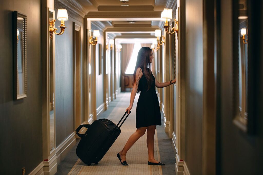 women entering a hotel room with her luggage