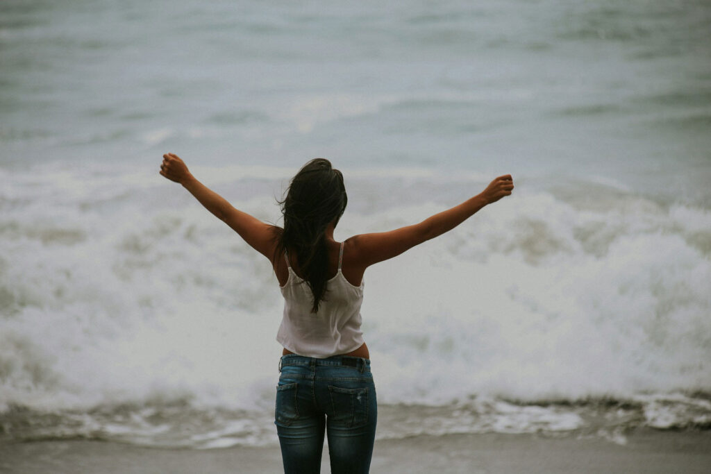 woman at the beach with her arms outstretched